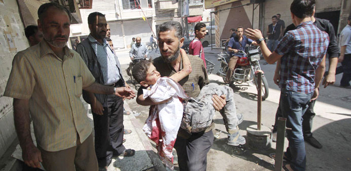 A man carries an injured boy after what activists said were two air strikes by regime forces in Douma, near Damascus yesterday.