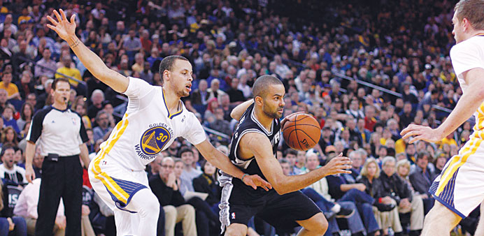 San Antonio Spurs guard Tony Parker (centre) dribbles the ball past Golden State Warriors guard Stephen Curry (30) in the third quarter at Oracle Aren
