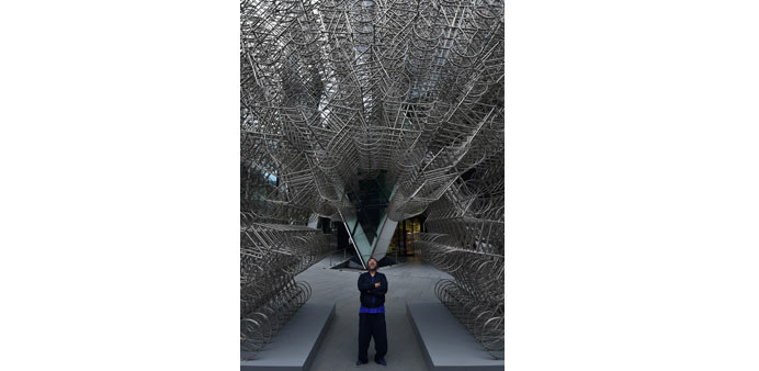 Ai Weiwei poses in front of his sculpture u201cForeveru201d at the base of the u201cGherkinu201d tower in the City of London yesterday during a photocall to celebrate
