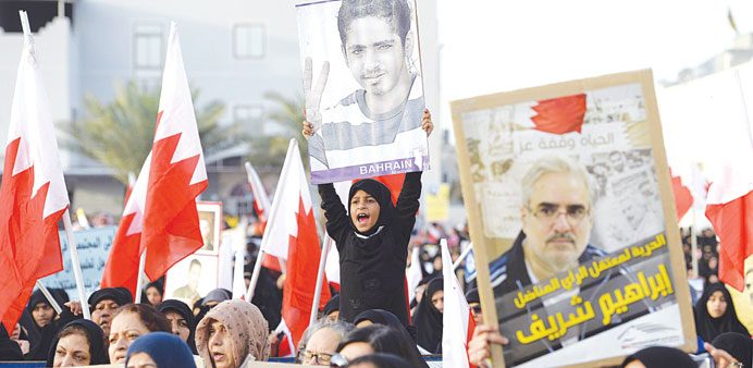 A girl holds a photo of a detained relative during a sit-in in Sar village, north of Manama, yesterday.