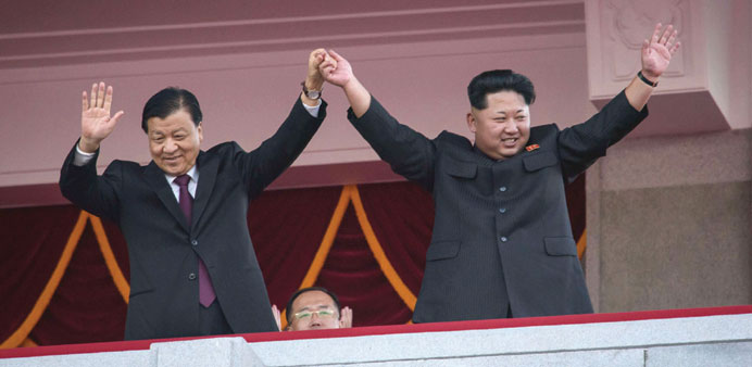 North Koreau2019s leader Kim Jong-Un and Chinese Politburo standing committee member Liu Yunshan (left) wave from a balcony towards participants of a mass