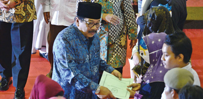 Surabaya Mayor Tri Rismaharini (centre in headscarf) accompanied by government officials speaks to several masked Indonesian sex workers from Surabaya