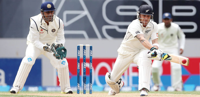New Zealand skipper Brendon McCullum reverse sweeps during his 224 as his Indian counterpart MS Dhoni (left) looks on in the first Test at Eden Park i