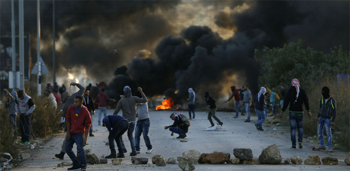 Palestinian protesters throw stones towards Israeli security forces during clashes