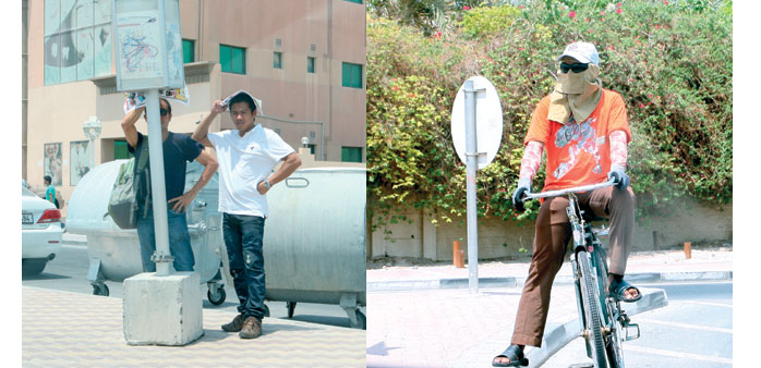 Two expatriates waiting for public transport at a bus stop a little after noon yesterday. Right: A cyclist on a Doha street yesterday. PICTURES: Shaji
