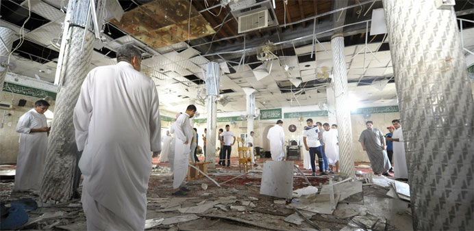 Saudi men gather around debris following a blast inside a mosque