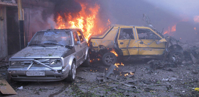 Cars burn after the bomb explosions in Homs yesterday.