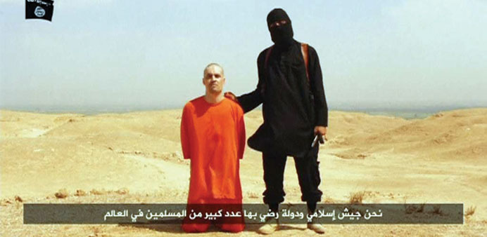 A masked Islamic State militant holding a knife speaks next to a man purported to be US journalist James Foley at an unknown location in this still im