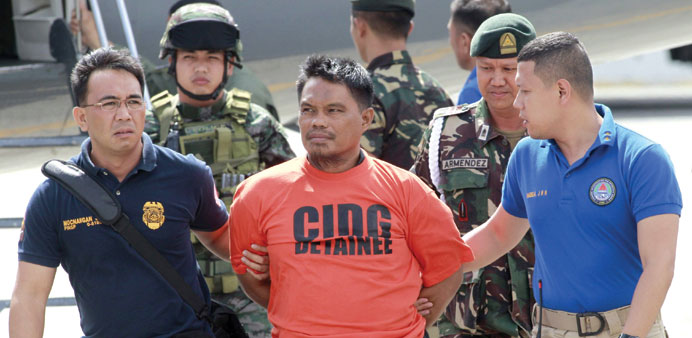 Members of the Philippine National Police (PNP) intelligence escort Mohamed Ali Tambako (centre), founder and leader of the Justice Islamic Movement, 