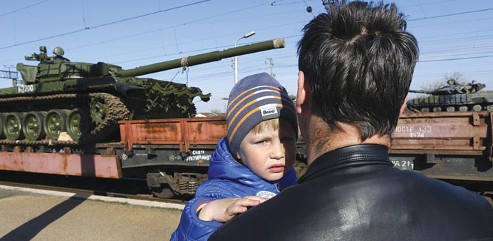 A father and son watching Russian tanks arriving onboard a train in the Crimean settlement of Gvardeiskoye near the city of Simferopol yesterday