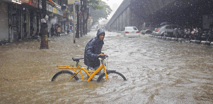 A man pushes his bicycle though a flooded road during rains in Mumbai yesterday.