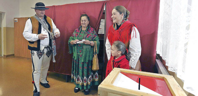 People in traditional outfits prepare to cast their ballots during the second round of presidential elections at a polling station in Zakopane, Poland