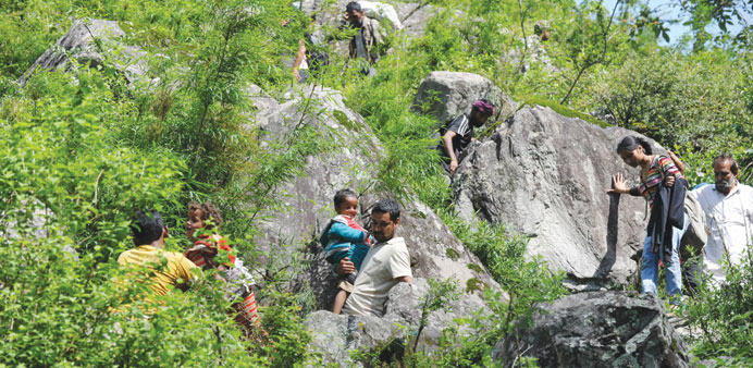 Stranded pilgrims coming from Badrinath make their way down a mountain at Govindghat yesterday.