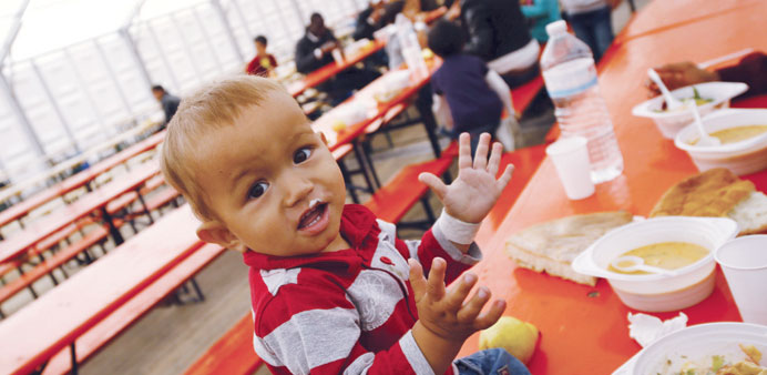 Migrants have lunch at a temporary shelter in a sports hall in Hanau yesterday.  