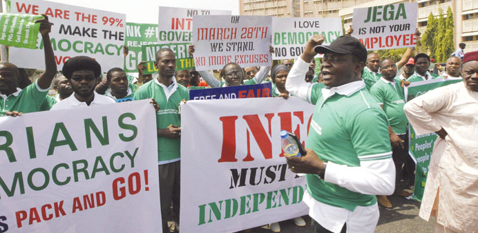 Members of the Nigerians United for Democracy Movement hold signs during a rally against any further election postponement in Abuja.