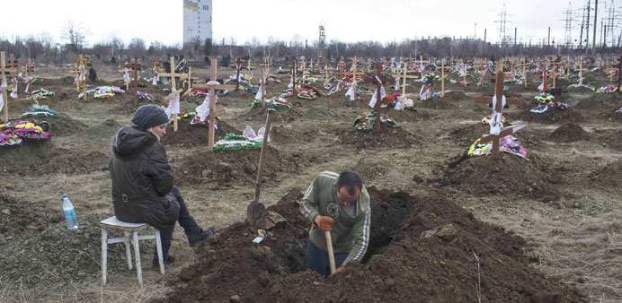 A grave digger works as his wife watches, at a cemetery where workers killed by a blast at the Zasyadko coal mine will be buried, in Donetsk.