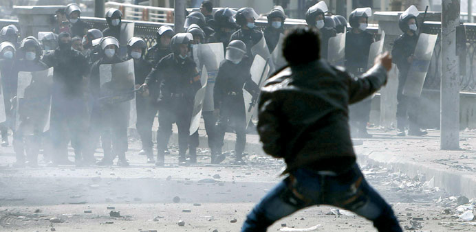 A protester gestures at riot police during clashes in Cairo yesterday.