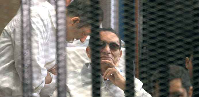 Gamal Mubarak (left) and brother Alaa with their father Hosni Mubarak in a cage inside the courtroom