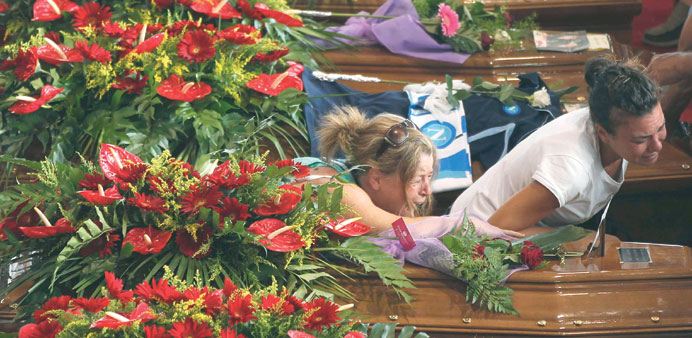 Women cry next to the coffins of victims of the coach crash during the funeral service.