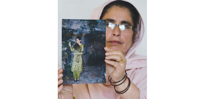 Gulnaz poses holding a photograph of her daughter Nazish Naz, who went missing in the 2005 Kashmir earthquake, in Muzaffarabad, the capital of Pakista