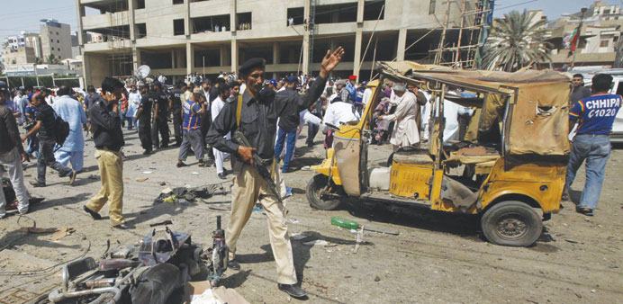 A policeman instructing people to move away from the site of an explosion at the Delhi Colony area in Karachi yesterday.