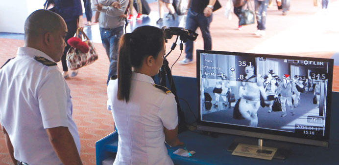 Filipino medical officers observe passengers from United Arab Emirates pass through a thermal scanner at the medical quarantine area upon arrival at t