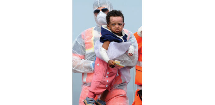 A rescuer carries an injured child as migrants disembark from military ship Bettica yesterday, in the port of Salerno, southern Italy.