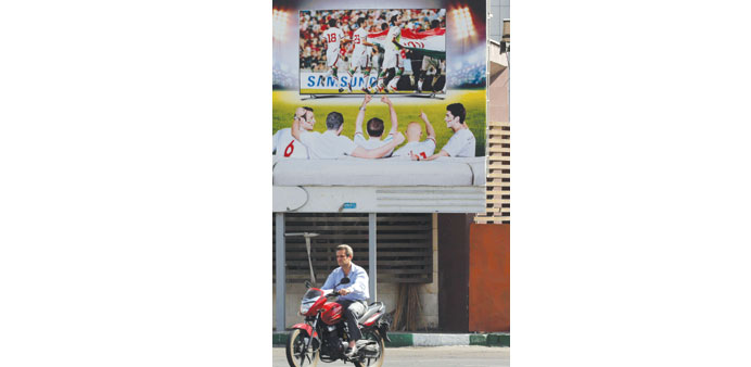 An Iranian man rides past a poster displaying support for Iranu2019s football team in Tehran. (AFP)