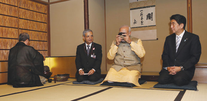 Prime Minister Narendra Modi enjoys a cup of green tea as his Japanese counterpart Shinzo Abe looks on during a tea ceremony at the Omotesenke tea hut