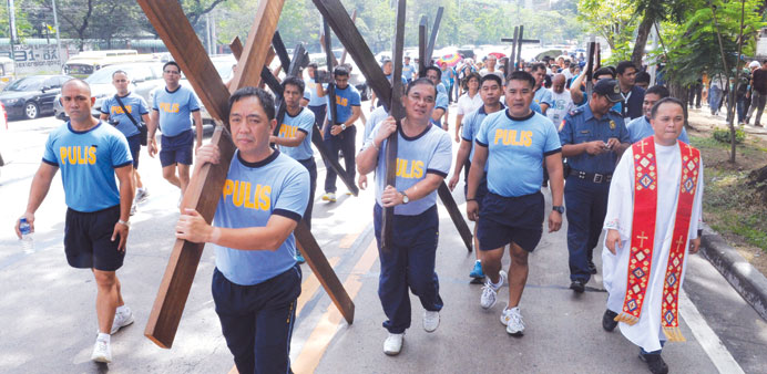 Police officers in the Philippine capital Manila carry wooden crosses yesterday to imitate the suffering of Jesus Christ and as a means to atone for t