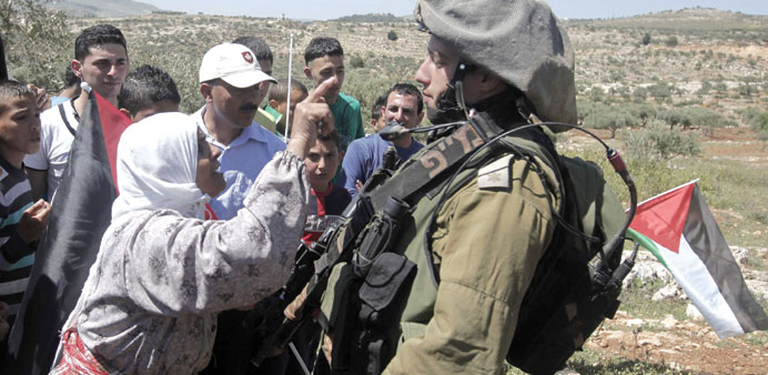 A Palestinian woman gestures while talking to an Israeli soldier during a weekly protest against the confiscation of land by Israel yesterday in the n