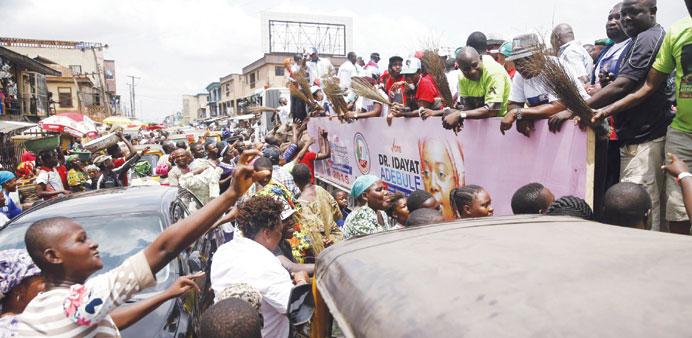 Party supporters give souvenirs to people as they ride on the back of a vehicle during an opposition party, the All Progressives Congress, campaign ev