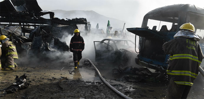 A team of Afghan firefighters work to contain fires at the site of a suspected suicide bomber that struck a parking lot