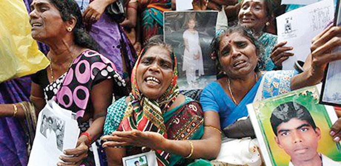 Tamil women cry as they hold up images of missing relatives at a protest in Jaffna.