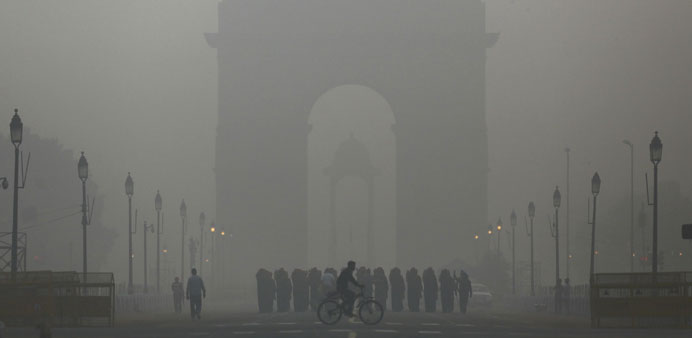 A man rides his bicycle next to soldiers marching in front of India Gate on a smoggy morning in New Delhi yesterday.