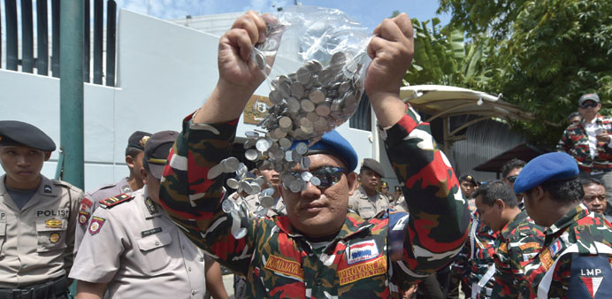 An Indonesian protester pours coins during a protest against Australian Prime Minister Tony Abbott and to support the executions of drug convicts on d