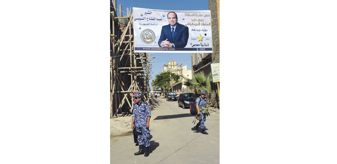Soldiers walk under an electoral banner for presidential candidate Abdel Fattah al-Sisi in Alexandria yesterday.