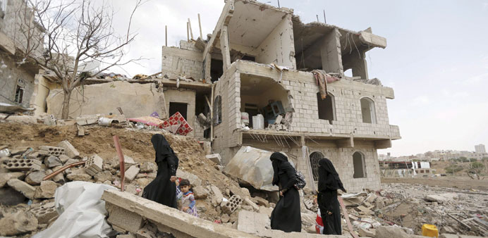 Women walk past a building damaged by an air strike in Sanaa yesterday.