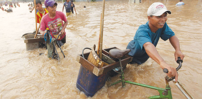 People wade through floodwaters in Jakarta yesterday. More than 10,000 people have been taken to temporary shelters.