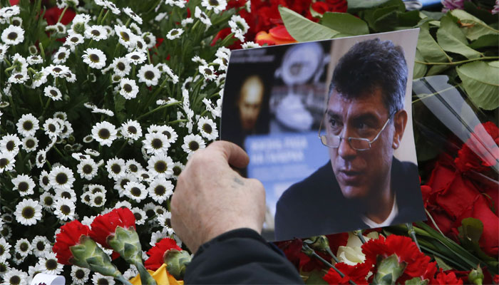 A visitor holds a photo at the site where Boris Nemtsov was recently murdered, in central Moscow 