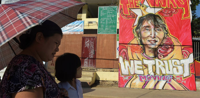 People walk past a graffiti depiction of Myanmar's Aung San Suu Kyi 