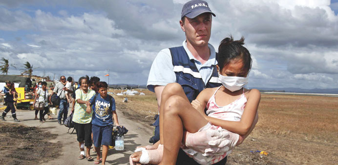 A volunteer from a French rescue team carries an injured girl to a military plane during an evacuation at Tacloban airport in the typhoon devastated c