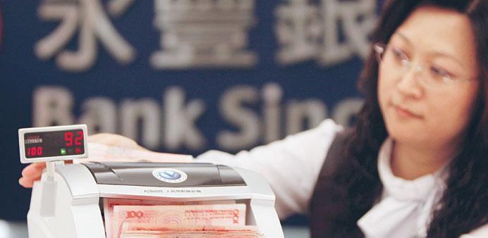 A Bank SinoPac employee counts yuan banknotes in a branch in Taipei. The yuan jumped to a record high against the dollar yesterday.