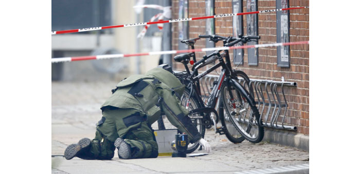  A bomb disposal expert examines an unattended package yesterday in front of the cafe in Copenhagen. No explosives were found.