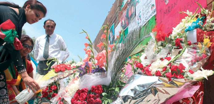 Supporters of Pakistani politician and former cricketer Imran Khan, place flowers outside a hospital where Khan is admitted in Lahore yesterday.