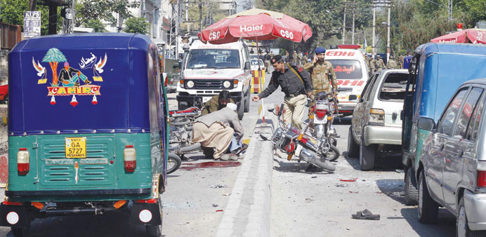 Security officials gather at the site of a bomb blast in Peshawar yesterday.