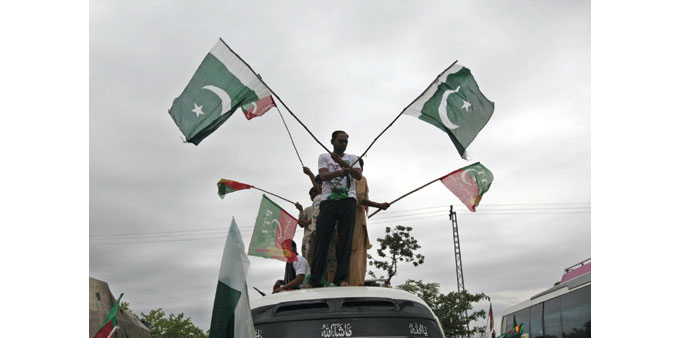    Supporters of Pakistan Tehreek-e-Insaf wave flags from the roof of a van at the end of the u2018Freedom Marchu2019 in Islamabad yesterday.
