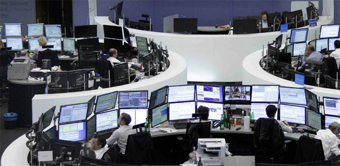 Traders are pictured at their desks in front of the DAX board at the stock exchange