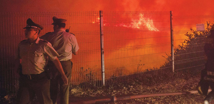 Police officers stand by while a forest fire burns the hills of Valparaiso city, northwest of Santiago.