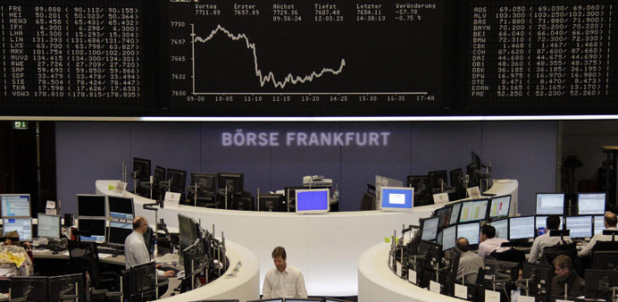 Traders are pictured at their desks in front of the DAX board at Frankfurt stock exchange yesterday. European stocks fell yesterday following news tha